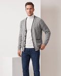 Man wearing a light gray marled knit V-neck cardigan sweater with black trim and jeans