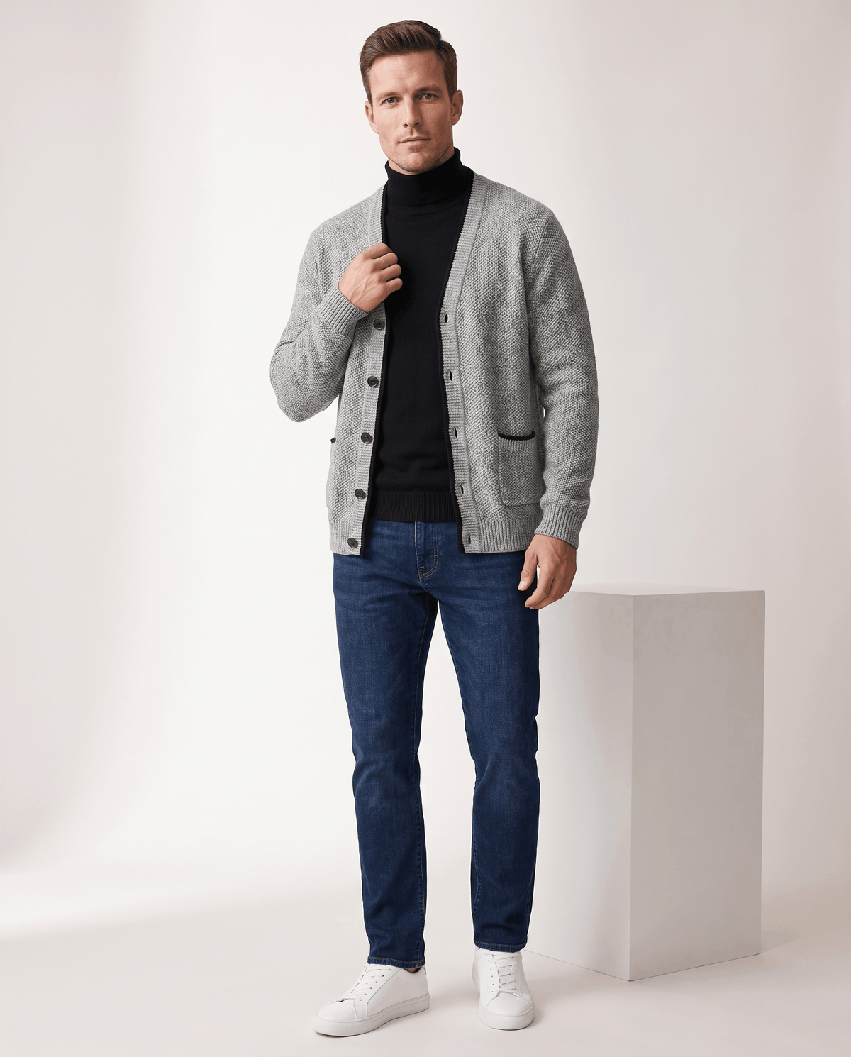 Full-length view of the light gray cardigan over a black turtleneck with jeans