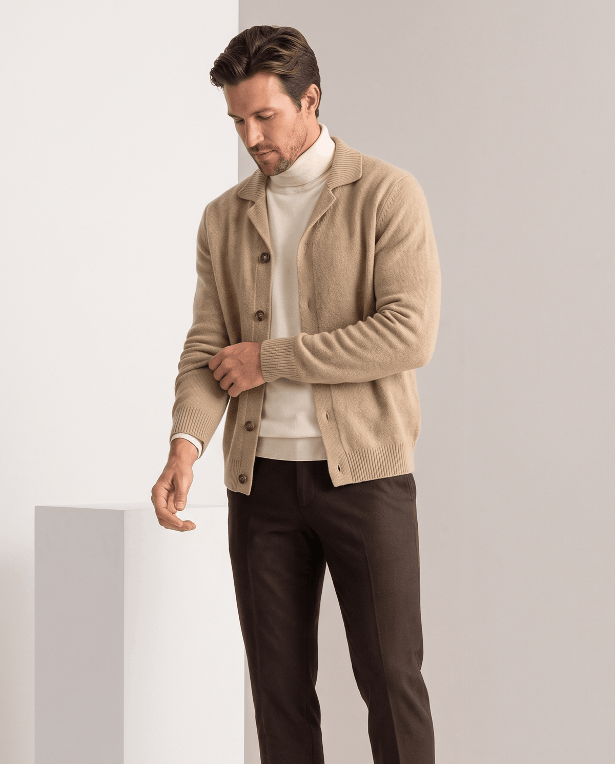 Camel collared cardigan worn open over a cream turtleneck with brown trousers