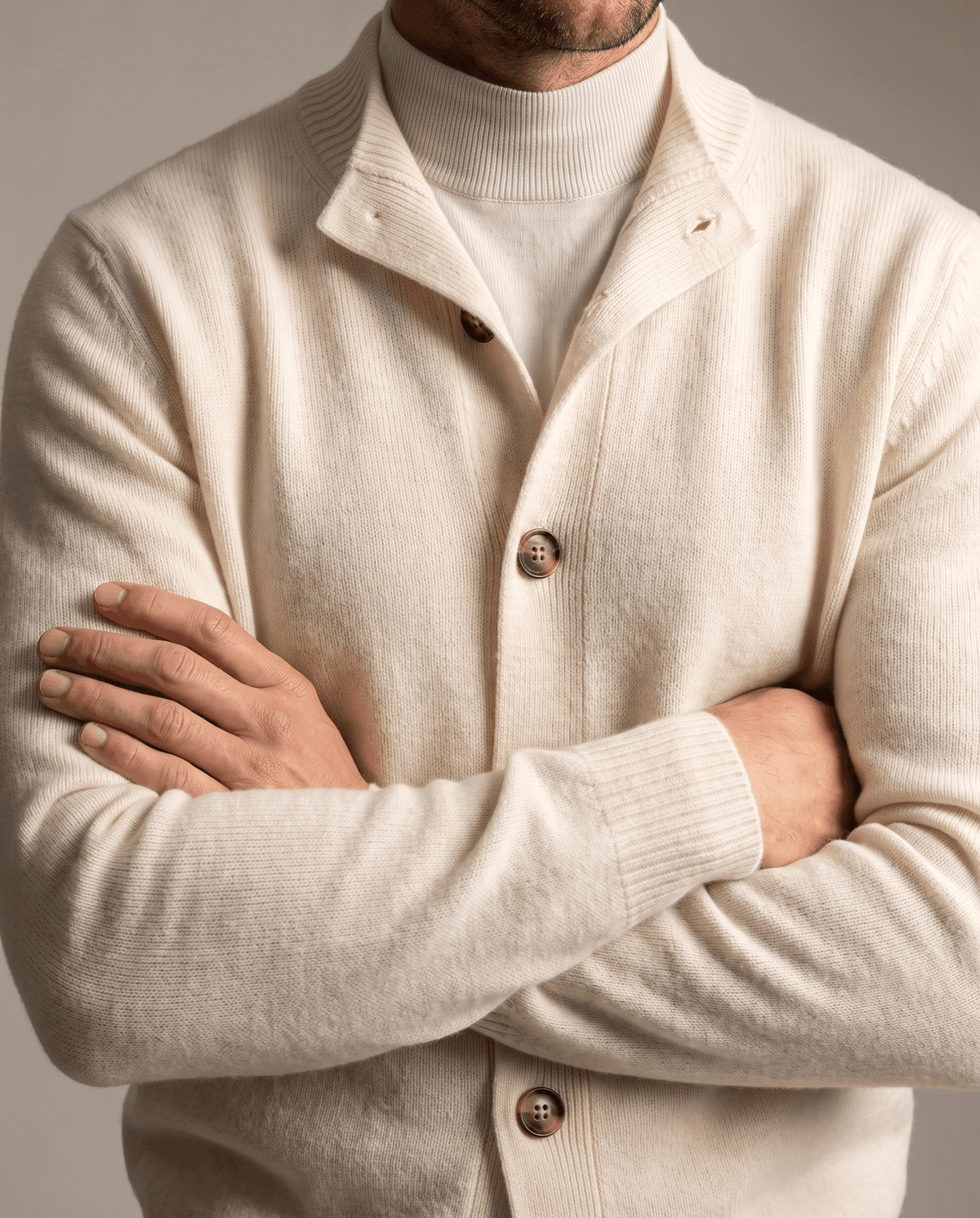 Close-up of the ivory cardigan collar and buttons over a cream turtleneck