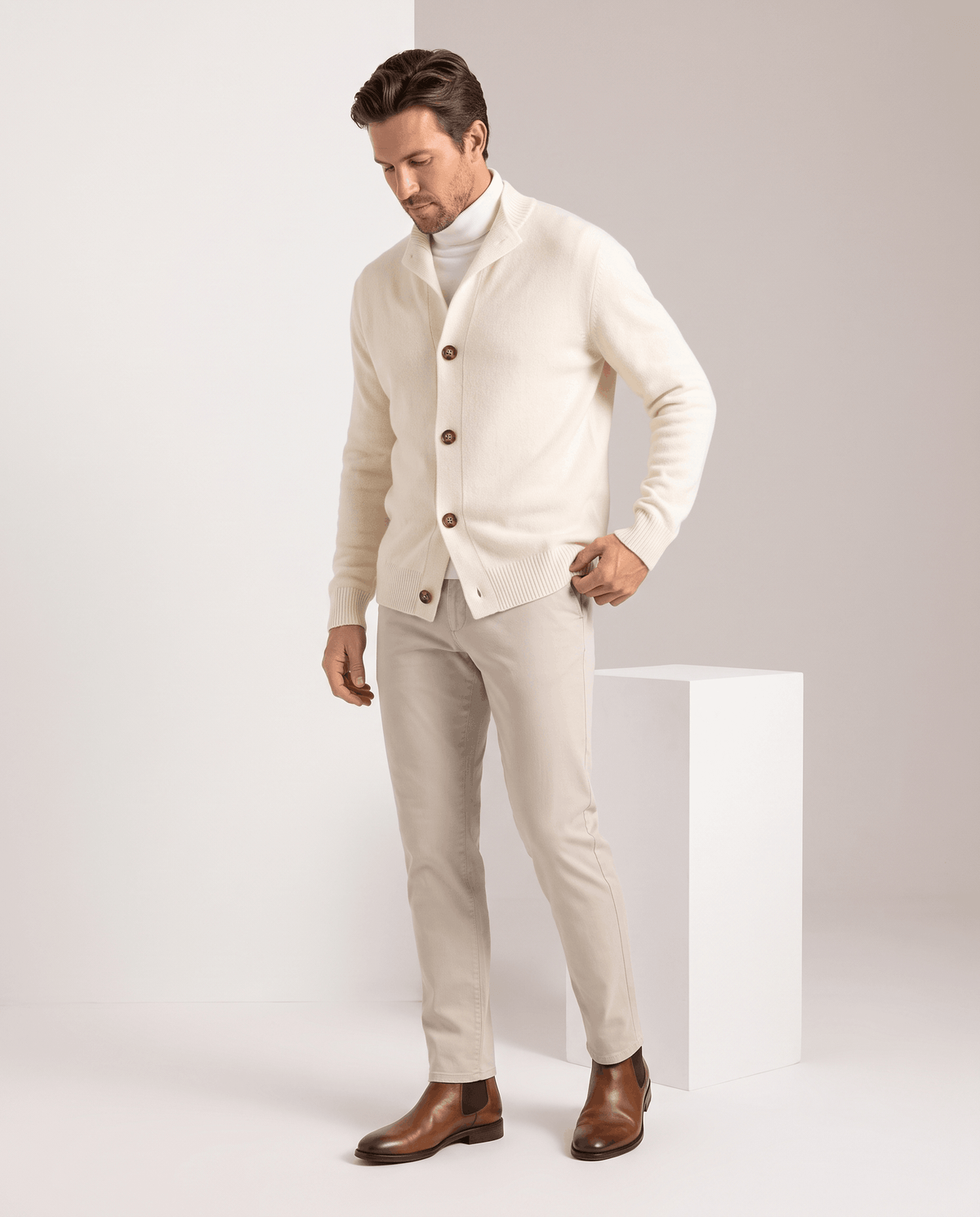 Full-length view of the ivory cardigan with one hand in the trouser pocket
