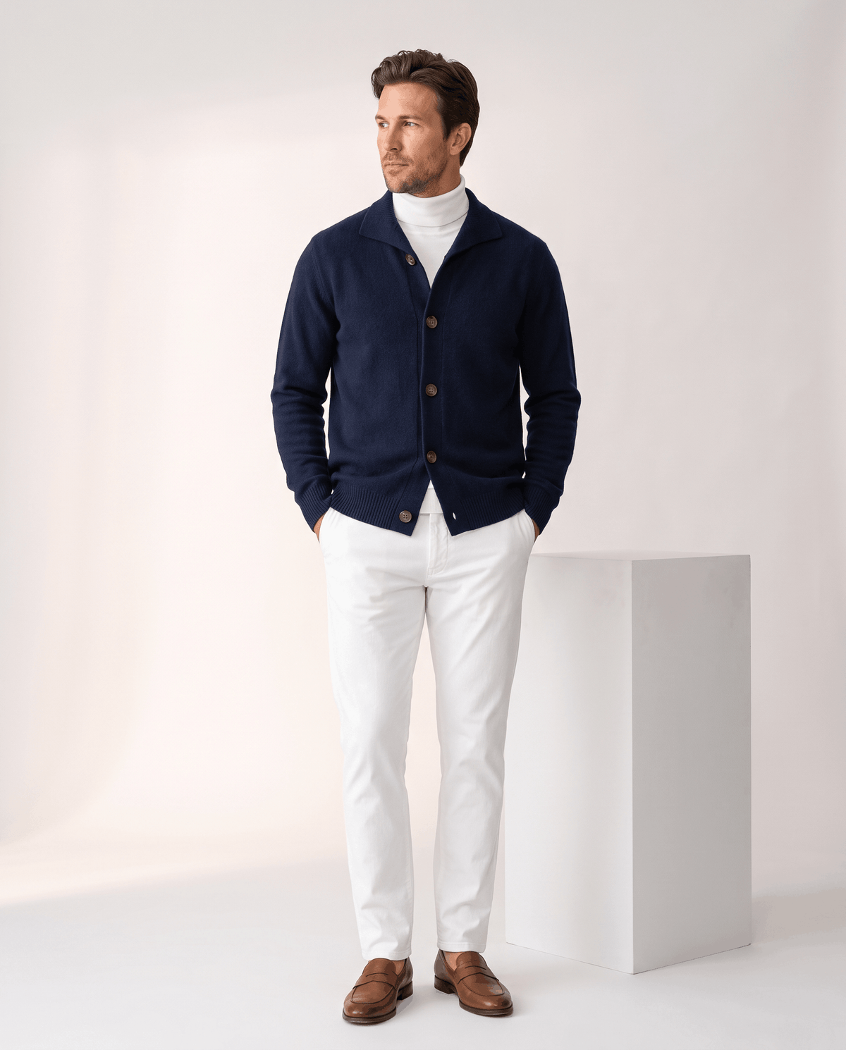 Full-length view of the navy cardigan with white trousers and brown shoes
