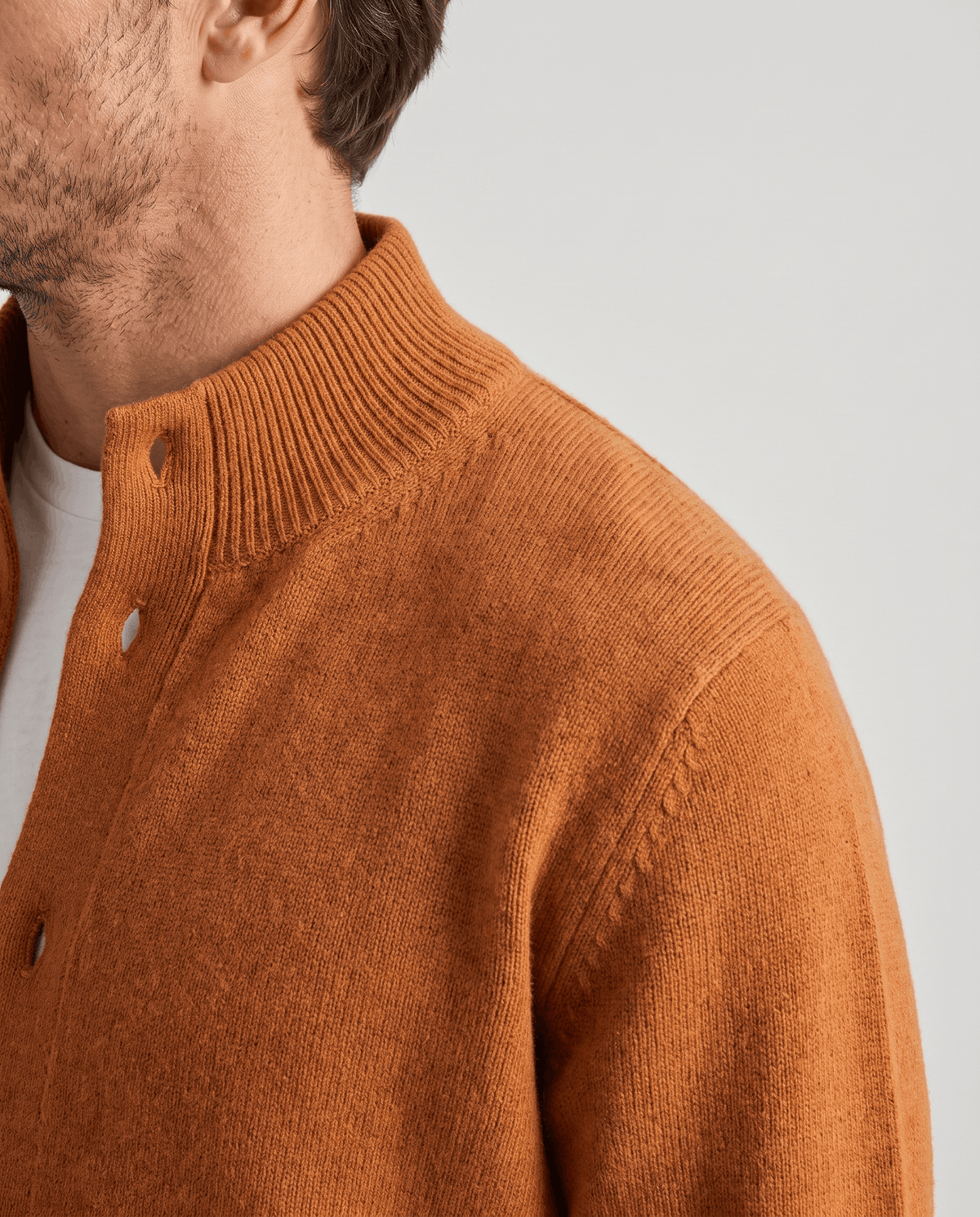 Side profile of the orange cardigan showing the ribbed collar and shoulder