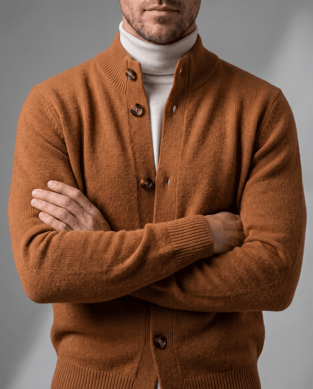 Arms crossed in an orange knit cardigan with buttons over a white turtleneck