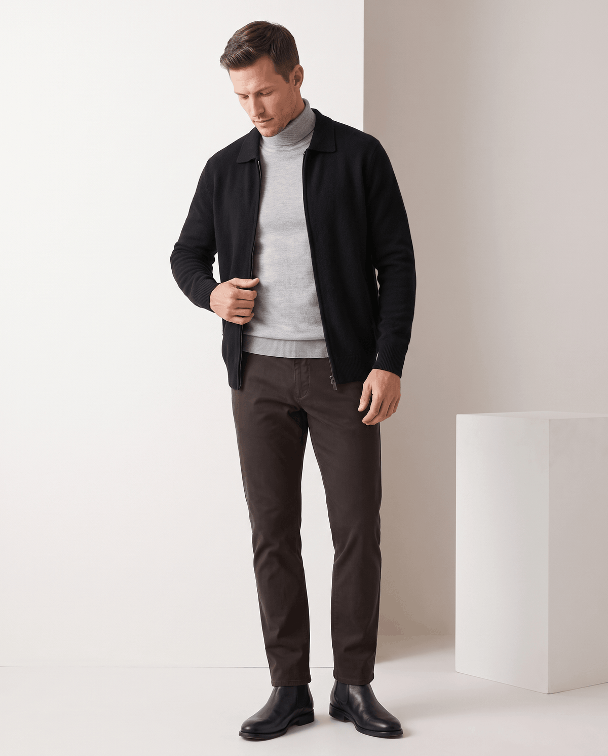 Full-length view of the black cardigan with a gray turtleneck and brown trousers