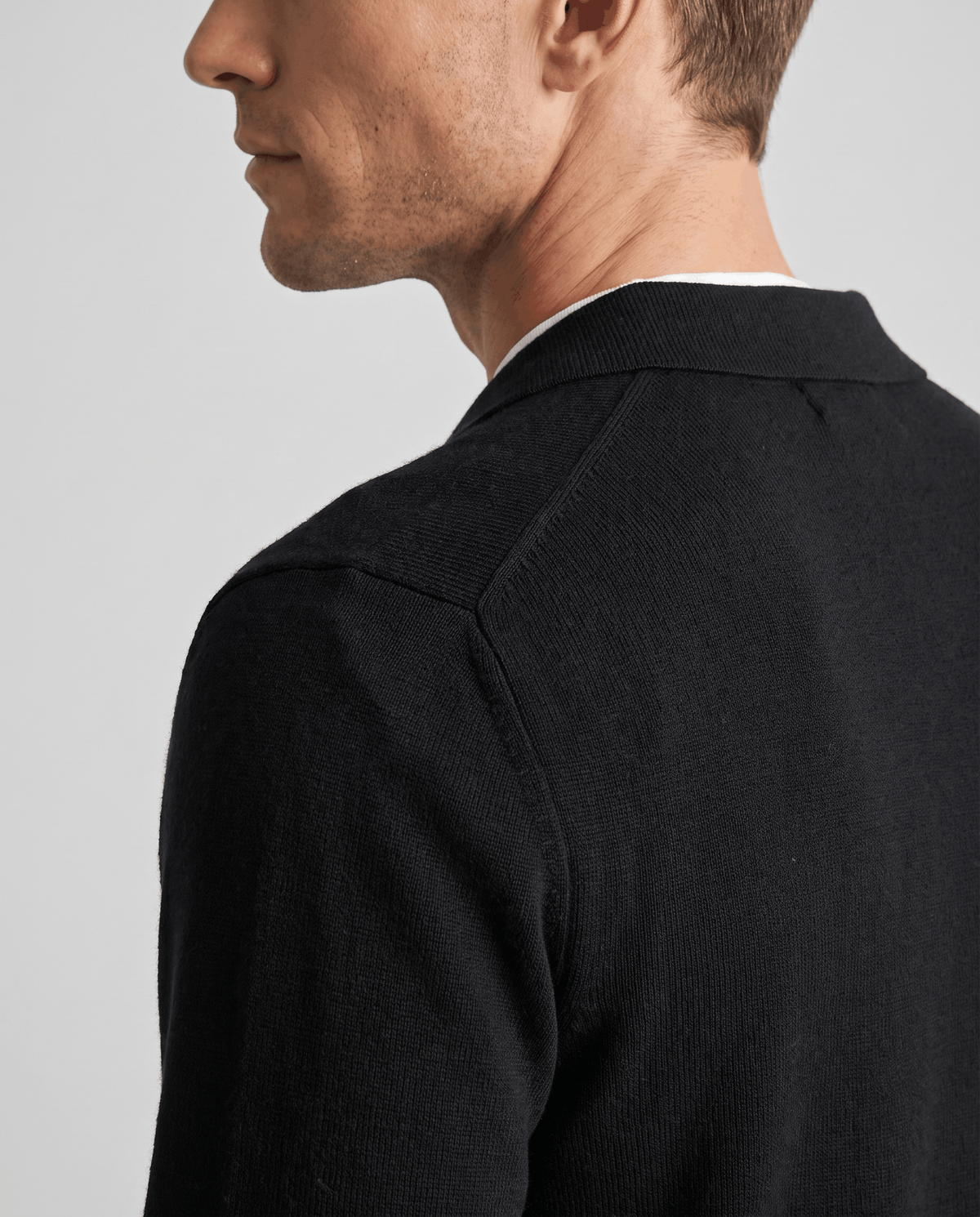 Side profile of the black knit cardigan showing the collar and shoulder