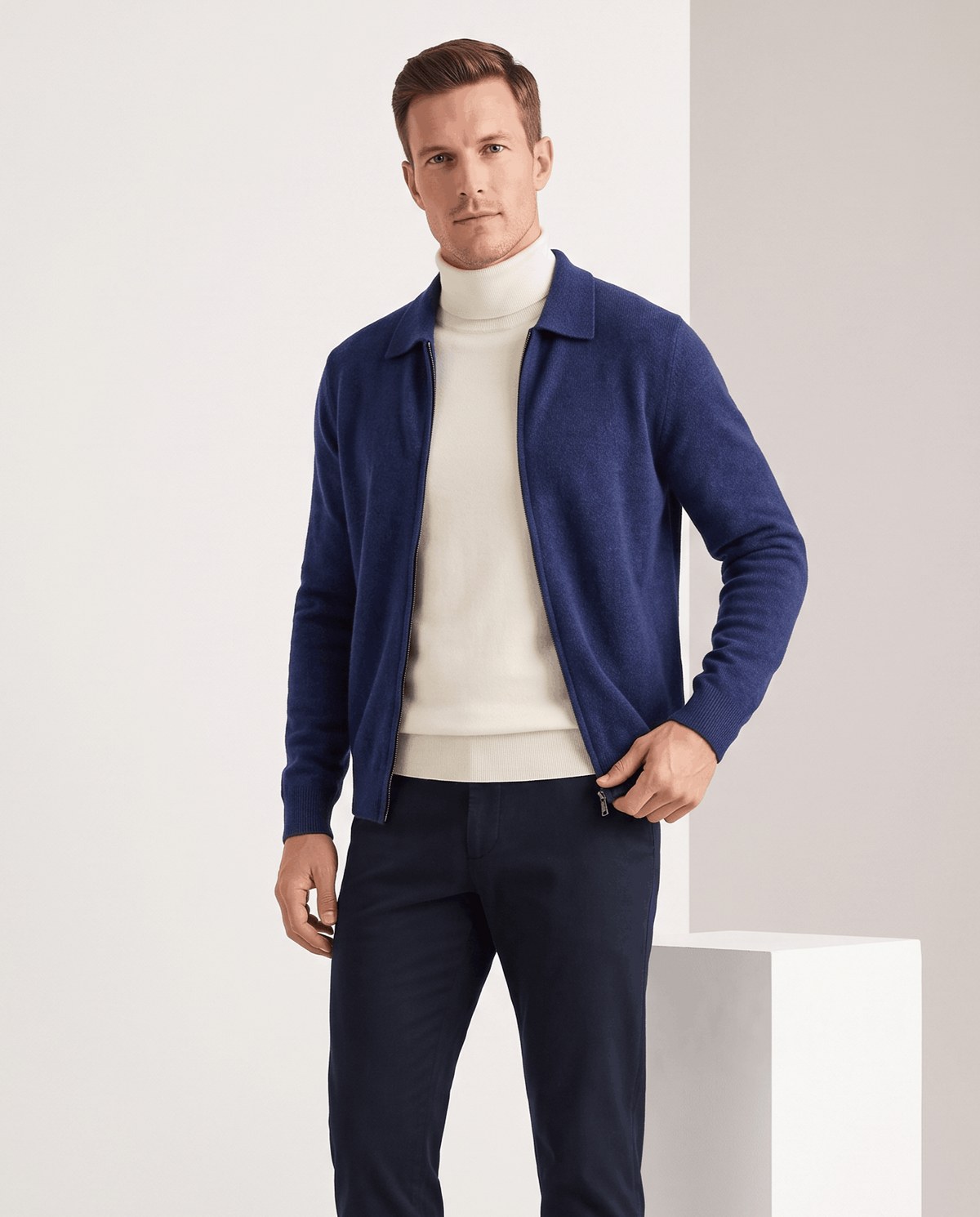 Navy zip cardigan worn open over a cream turtleneck with dark trousers