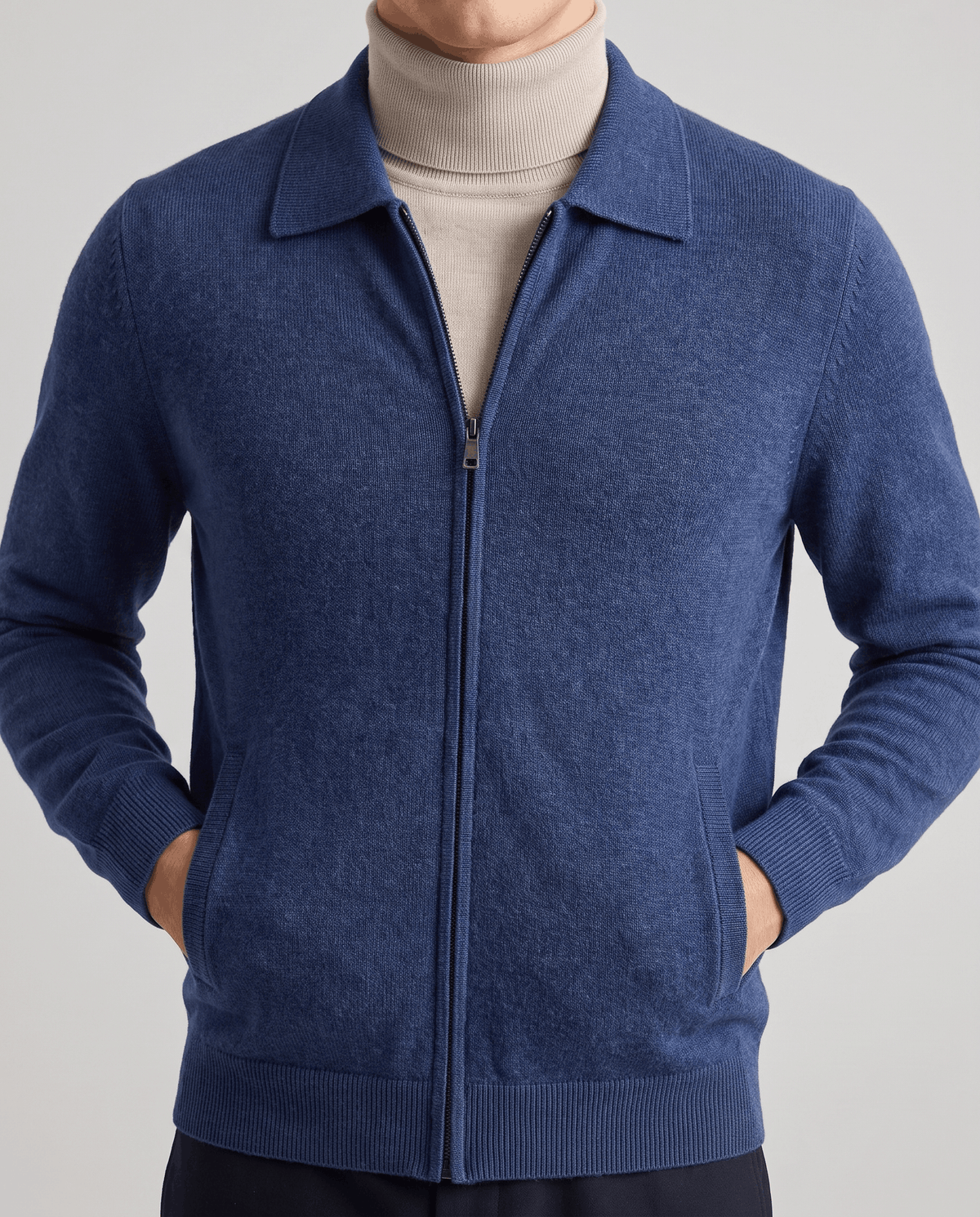 Navy merino zip cardigan with hands in the side pockets over a beige turtleneck