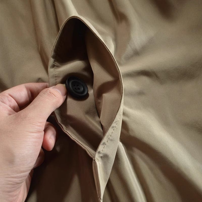 Close-up of a hand holding the inner button fastening on a beige trench coat