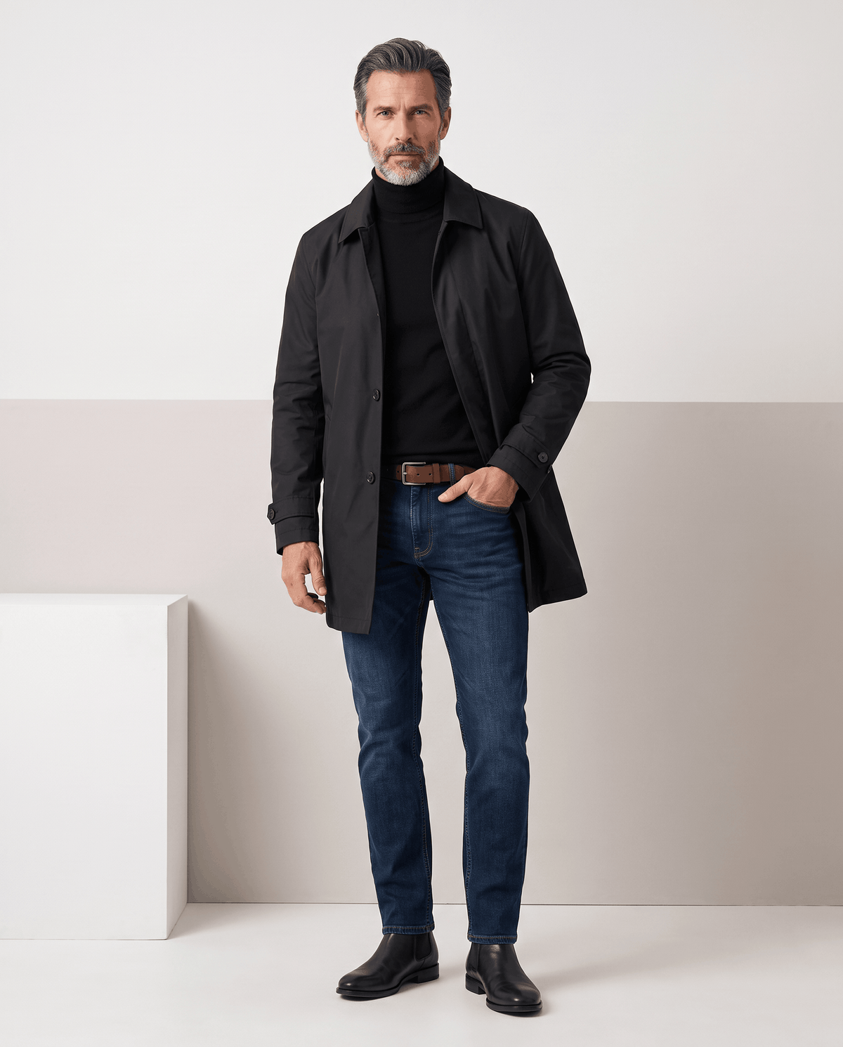 Full-length black trench coat styled with a black roll-neck, jeans and black shoes