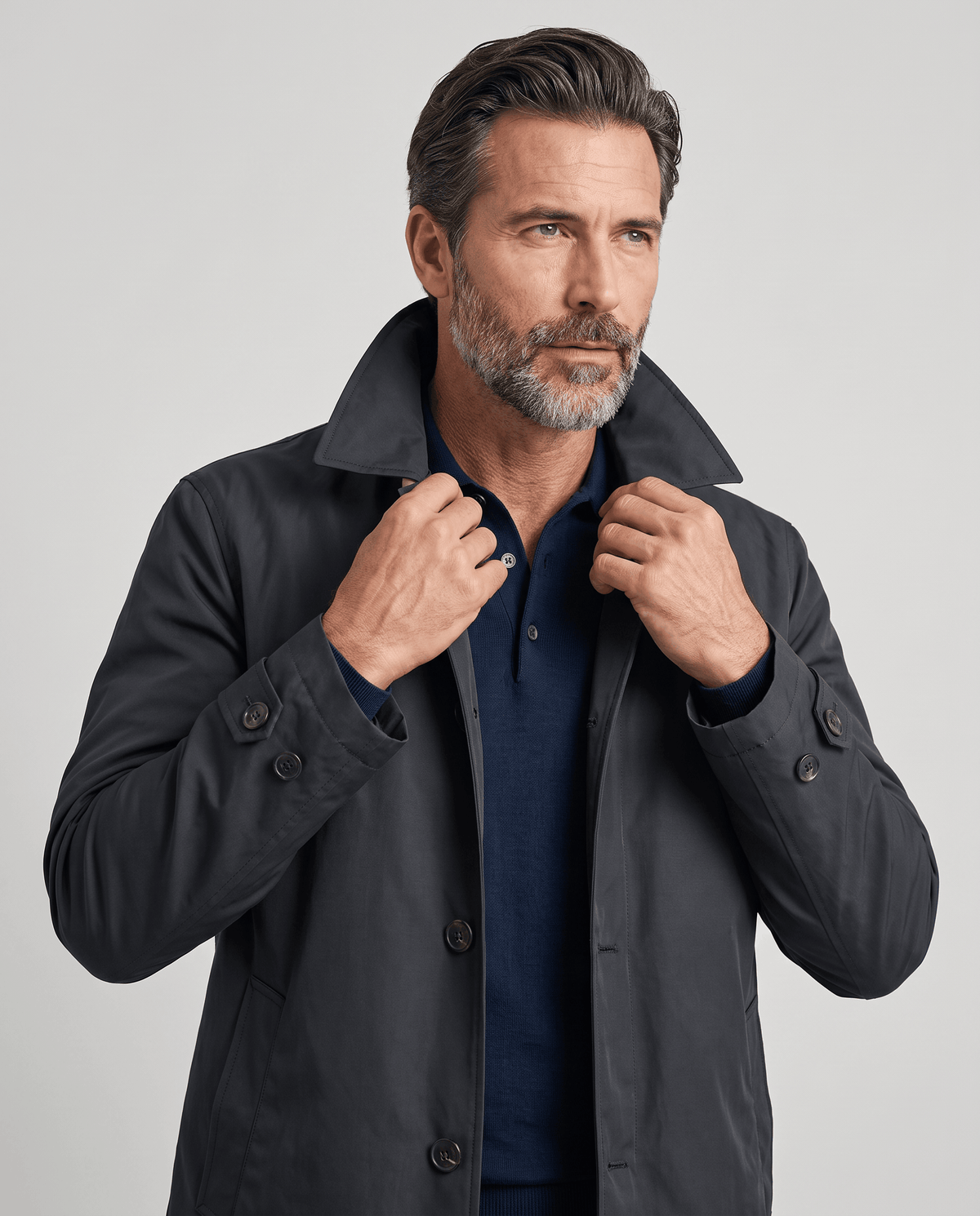 Gray trench coat with collar turned up, worn open over a navy shirt