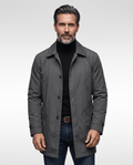 Man wearing a gray mid-length trench coat over a black roll-neck and jeans