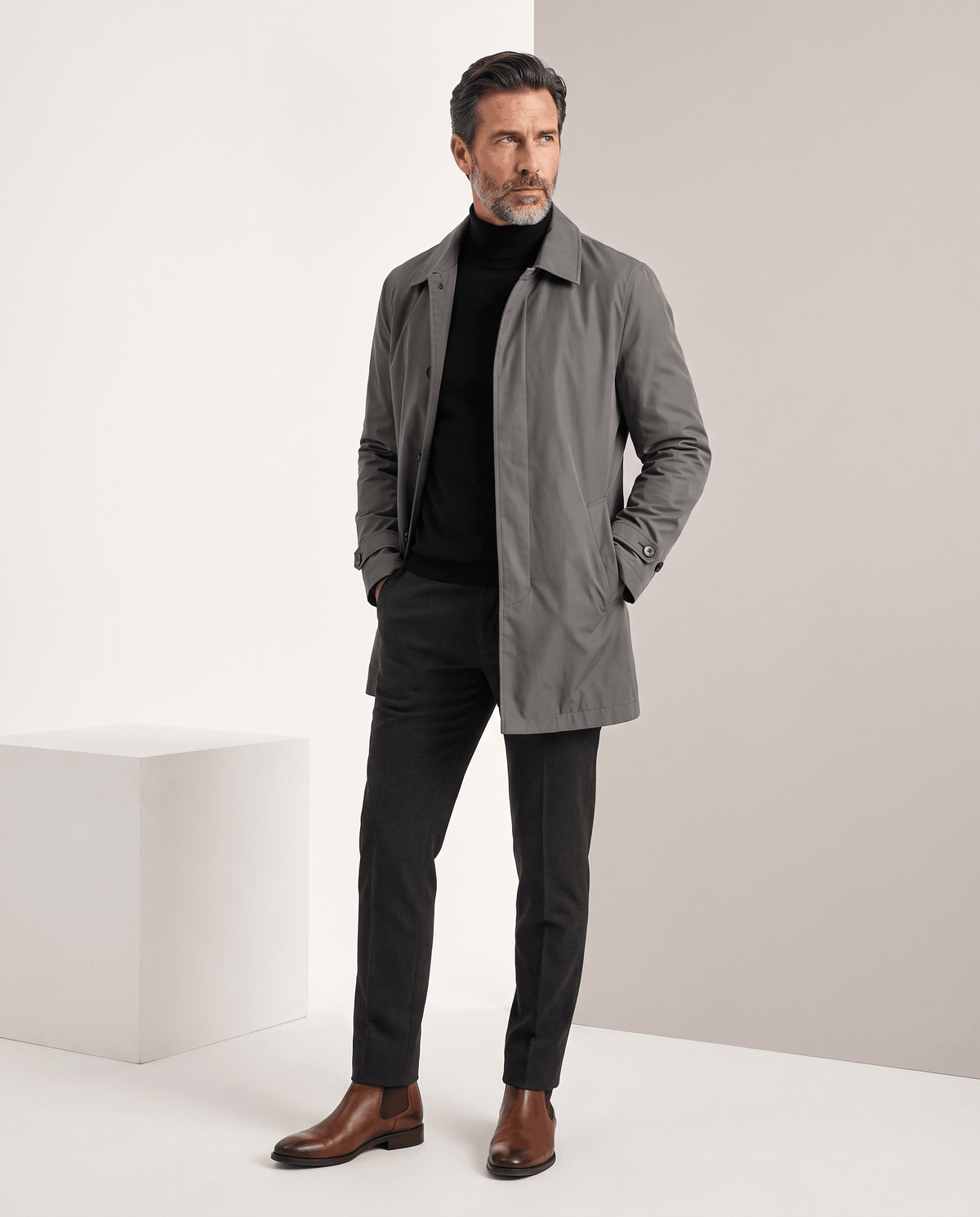 Full-length view of a gray trench coat styled with dark trousers and brown shoes