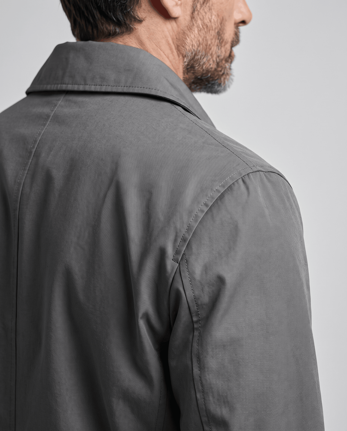 Close-up of the shoulder seam and sleeve on a gray trench coat