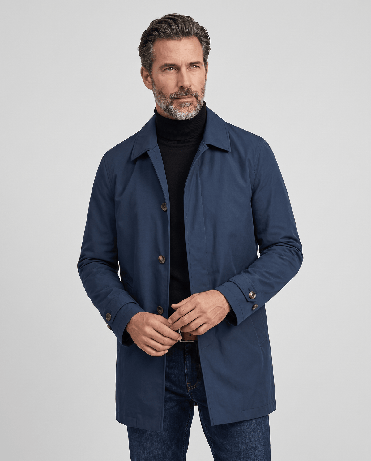 Navy blue trench coat worn buttoned over a black roll-neck sweater