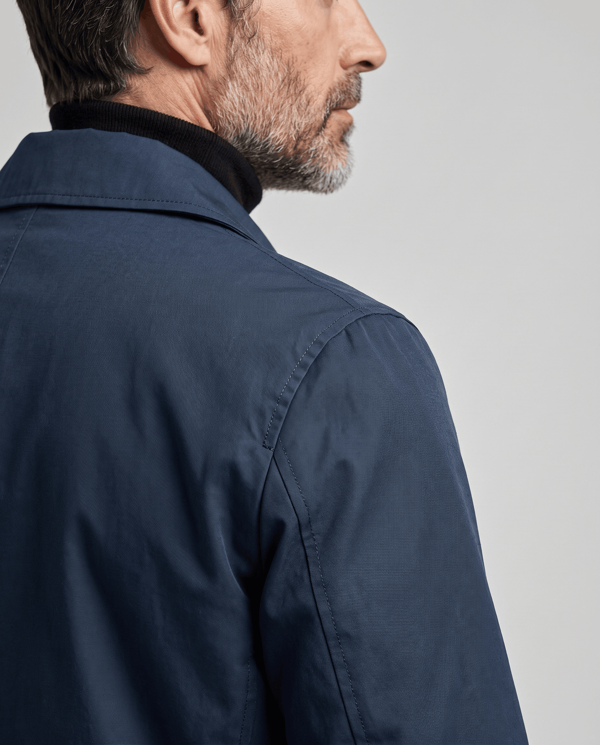 Close-up of the shoulder and spread collar on a navy blue trench coat