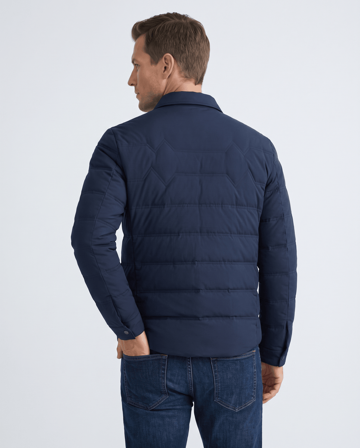 Back view of a man wearing a navy quilted puffer jacket