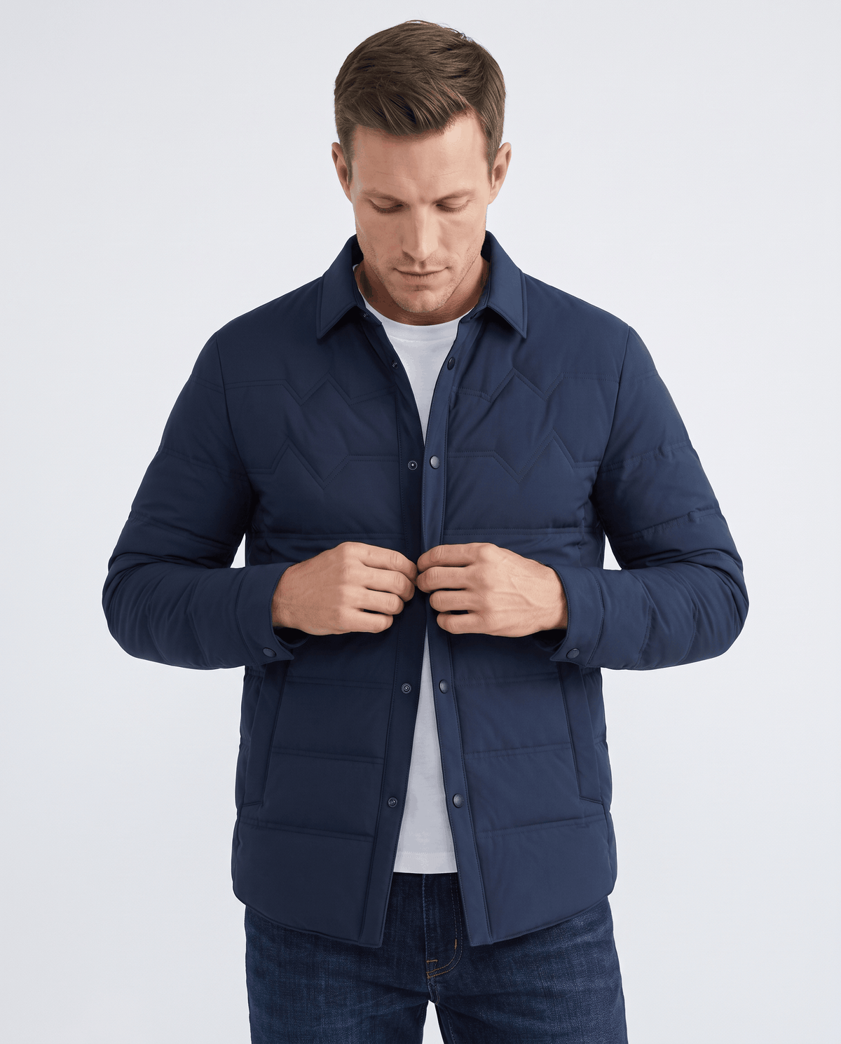 Man fastening the snap front of a navy quilted duck down puffer jacket