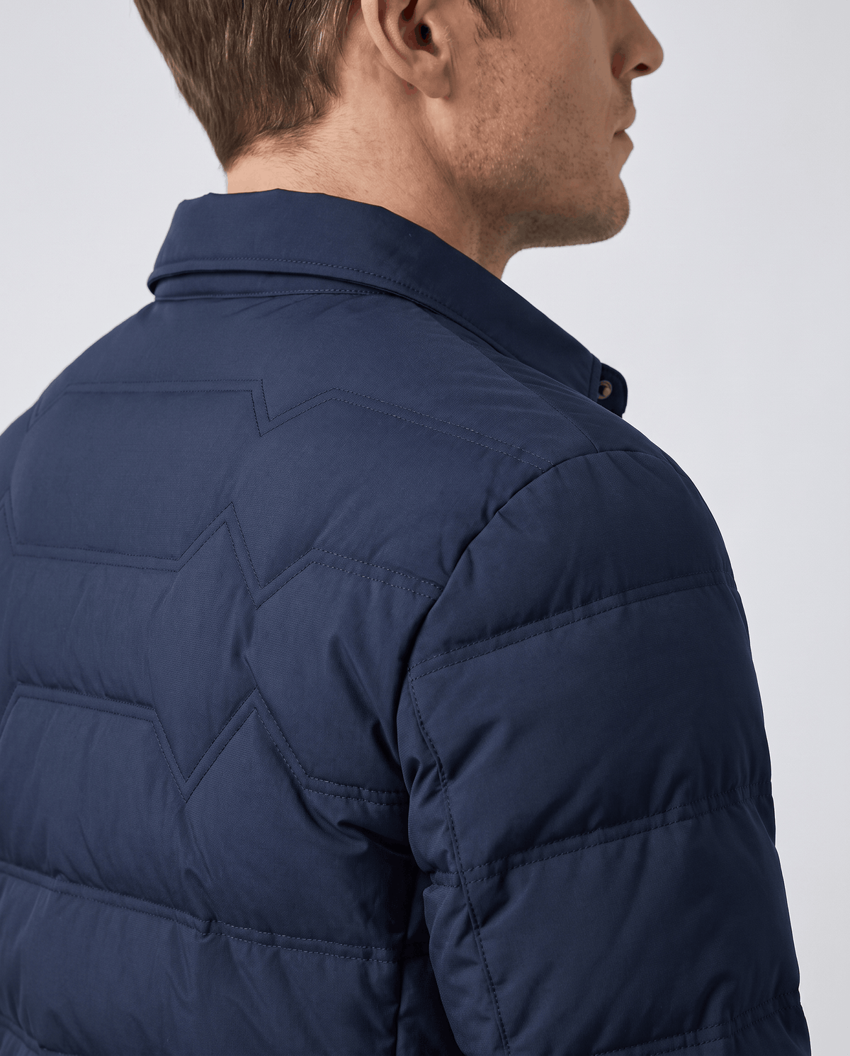 Close-up of the quilted shoulder and sleeve on a navy puffer jacket