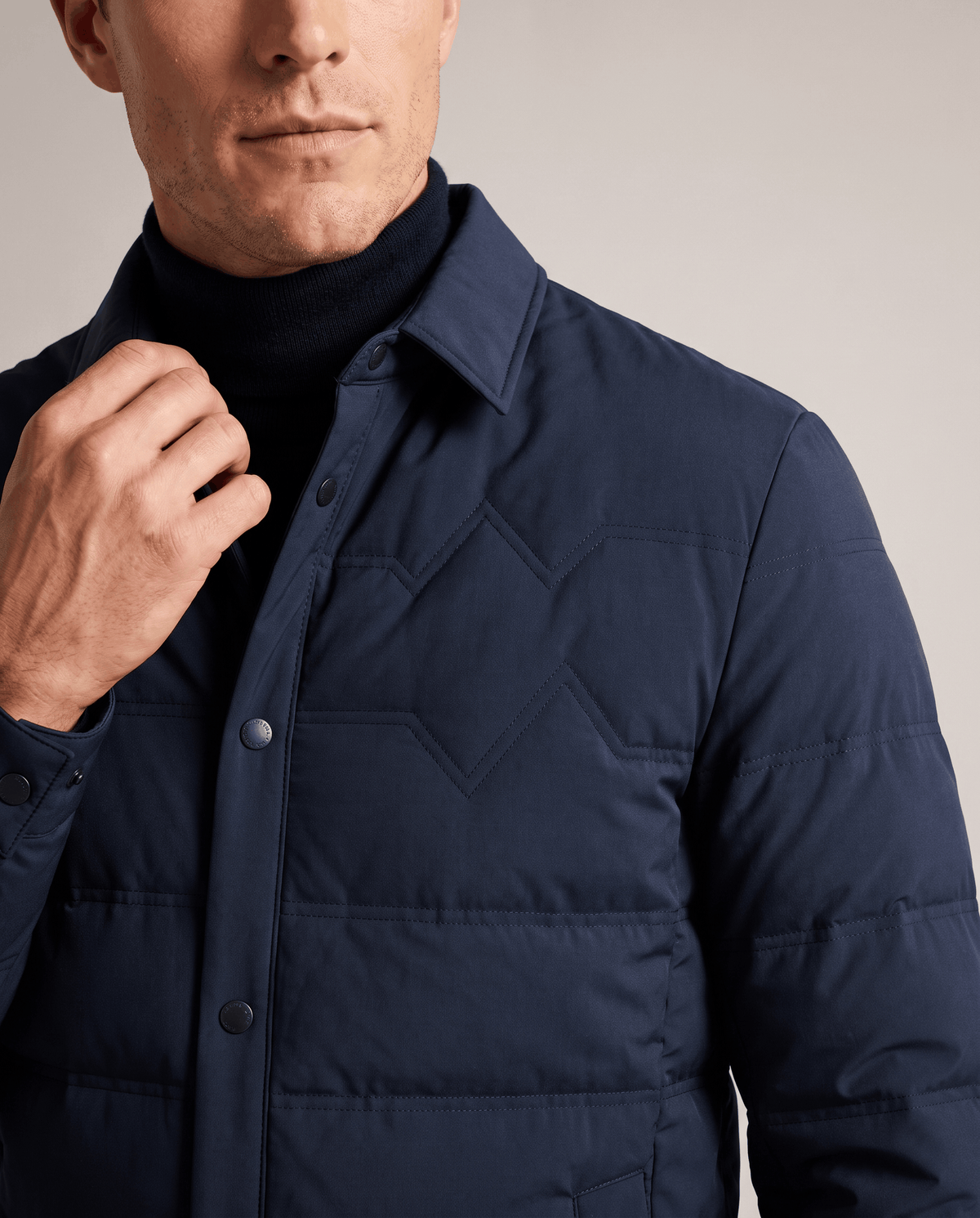 Close-up of the point collar and snap placket on a navy puffer jacket