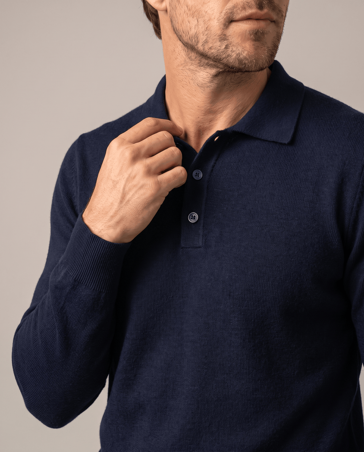 Hand on the button placket of the Elias navy wool knit polo sweater