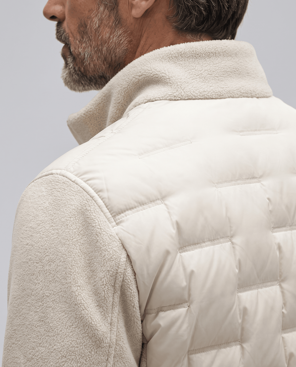 Close-up of the quilted panel and fleece sleeve on an off-white puffer jacket