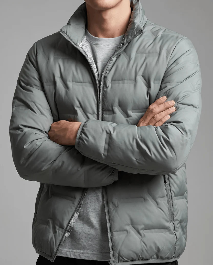 Man with arms crossed in a zipped olive green quilted puffer jacket