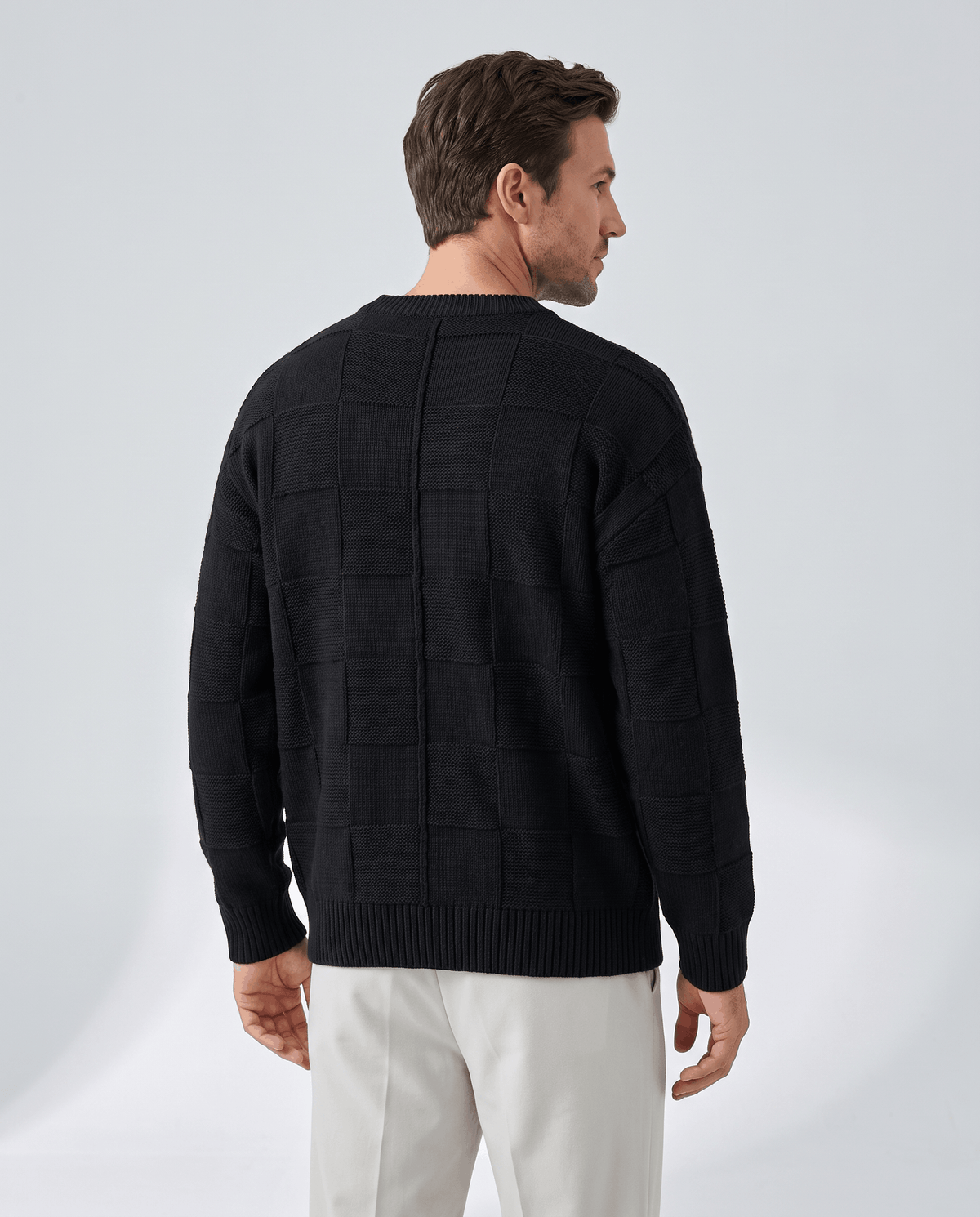 Back view of black oversized knit pullover with white trousers