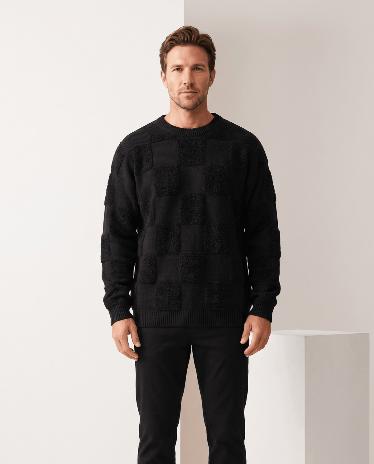 Model in black oversized checkerboard knit sweater with black trousers