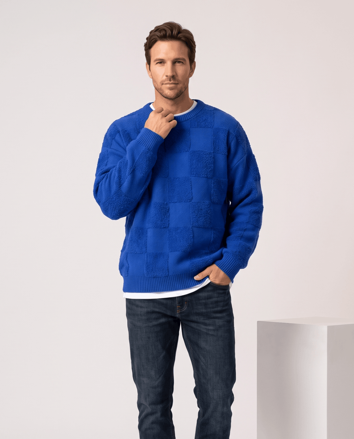 Man wearing men's oversized checkerboard knit sweater in blue with dark jeans