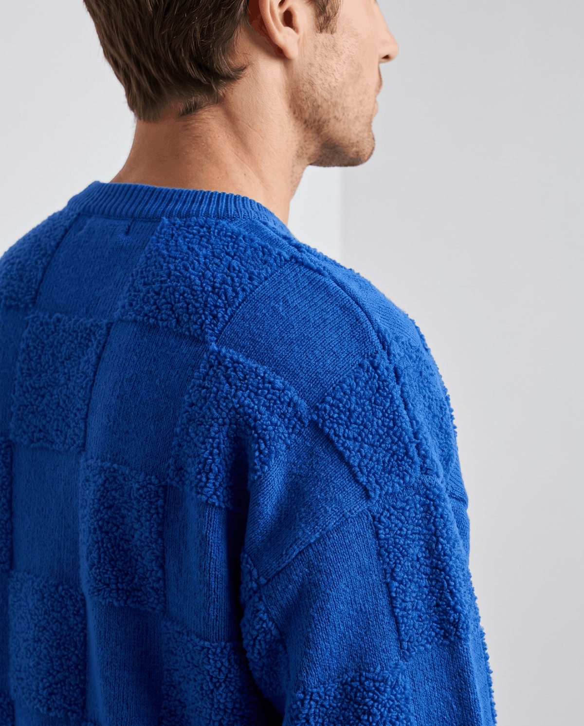 Shoulder close-up of blue sweater showing textured square pattern