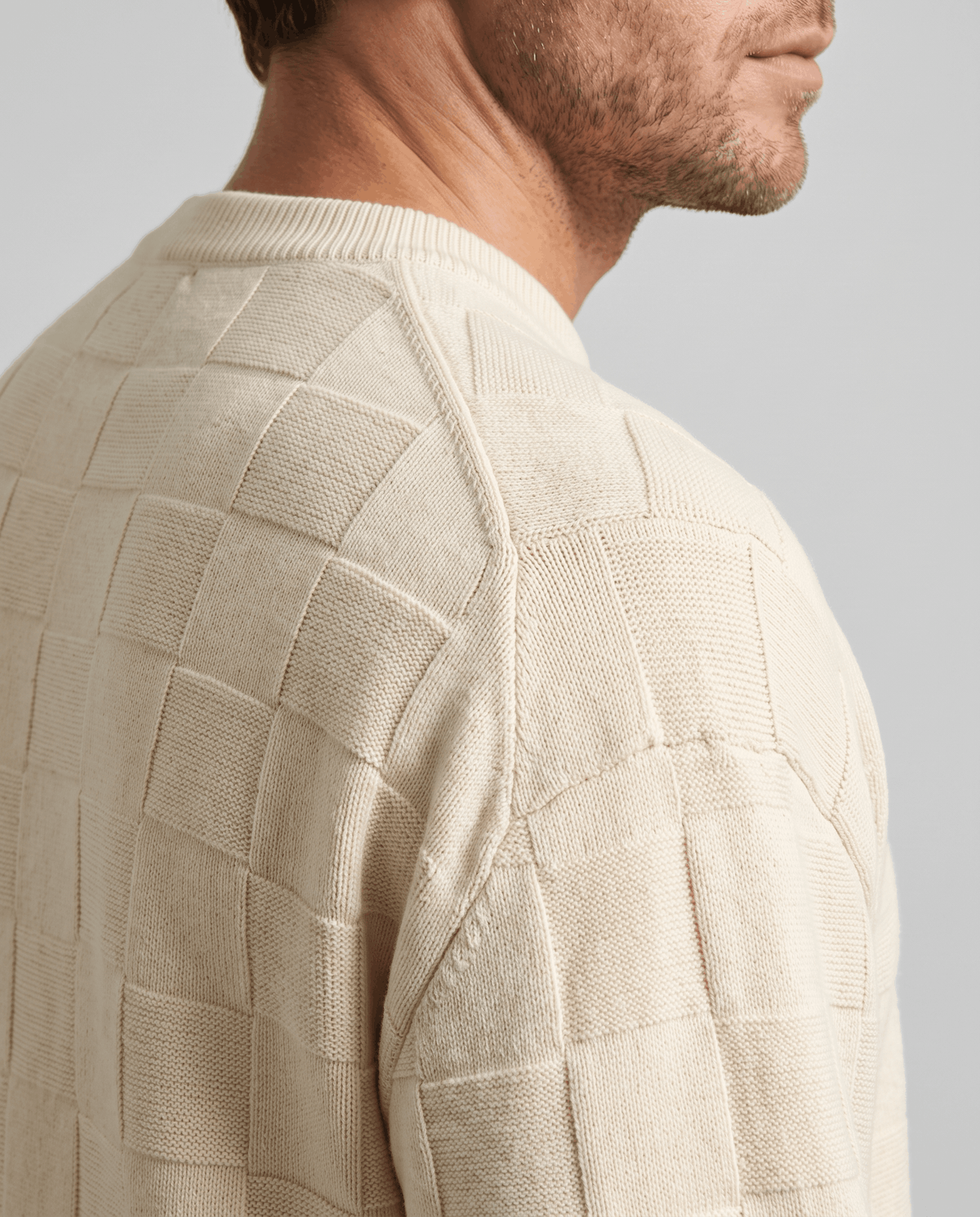 Shoulder close-up of cream sweater showing raised square texture