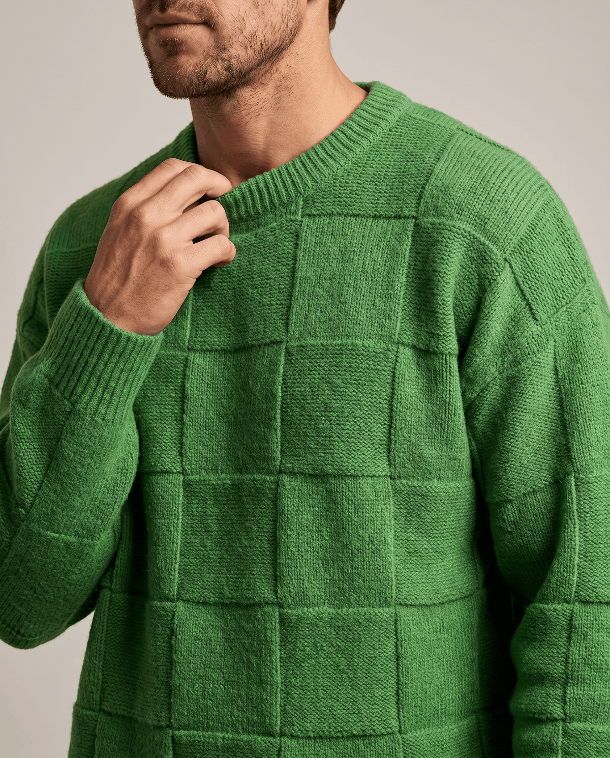 Front close-up of green tonal checkerboard knit with ribbed crew neck