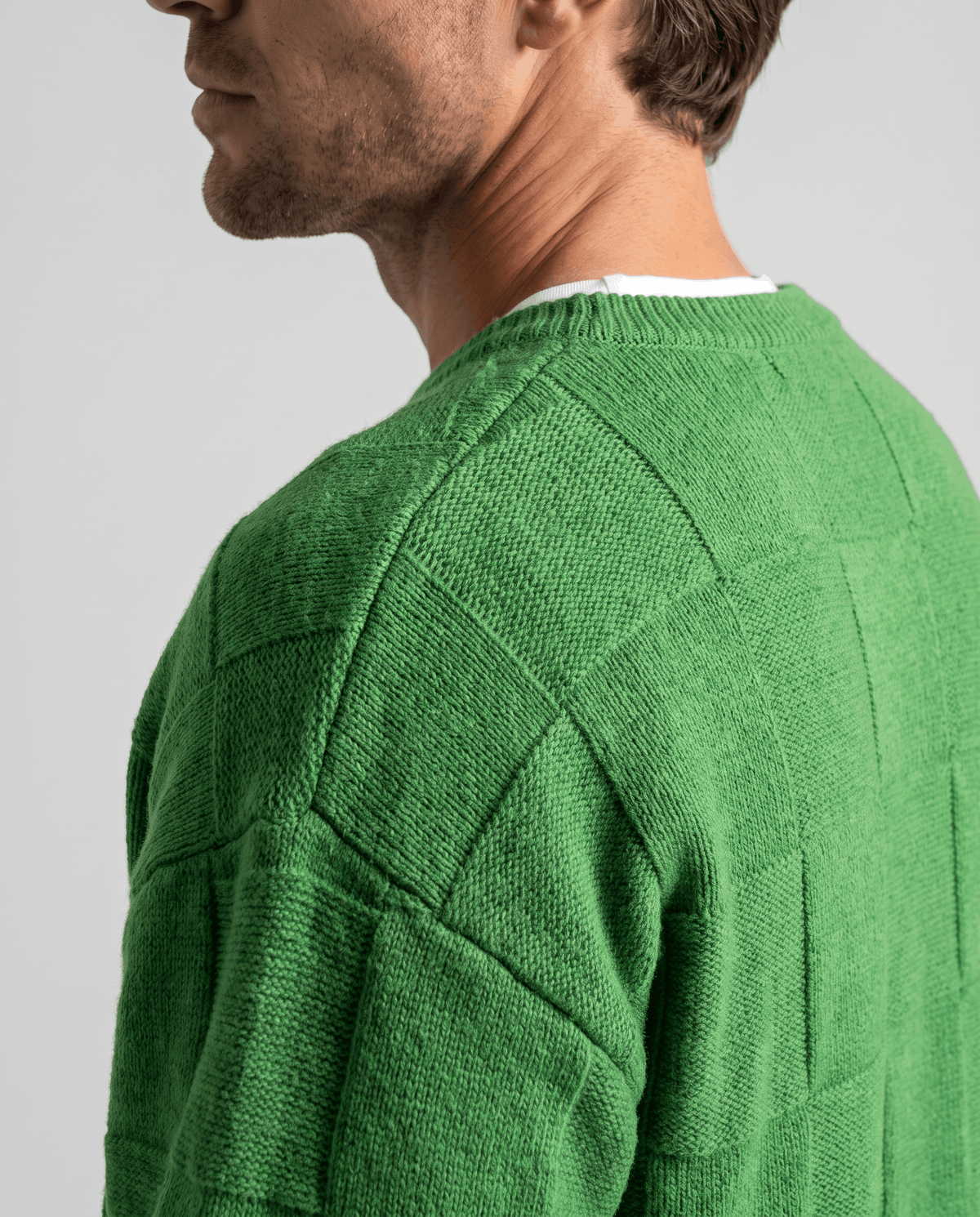 Side close-up of green sweater shoulder over a white tee