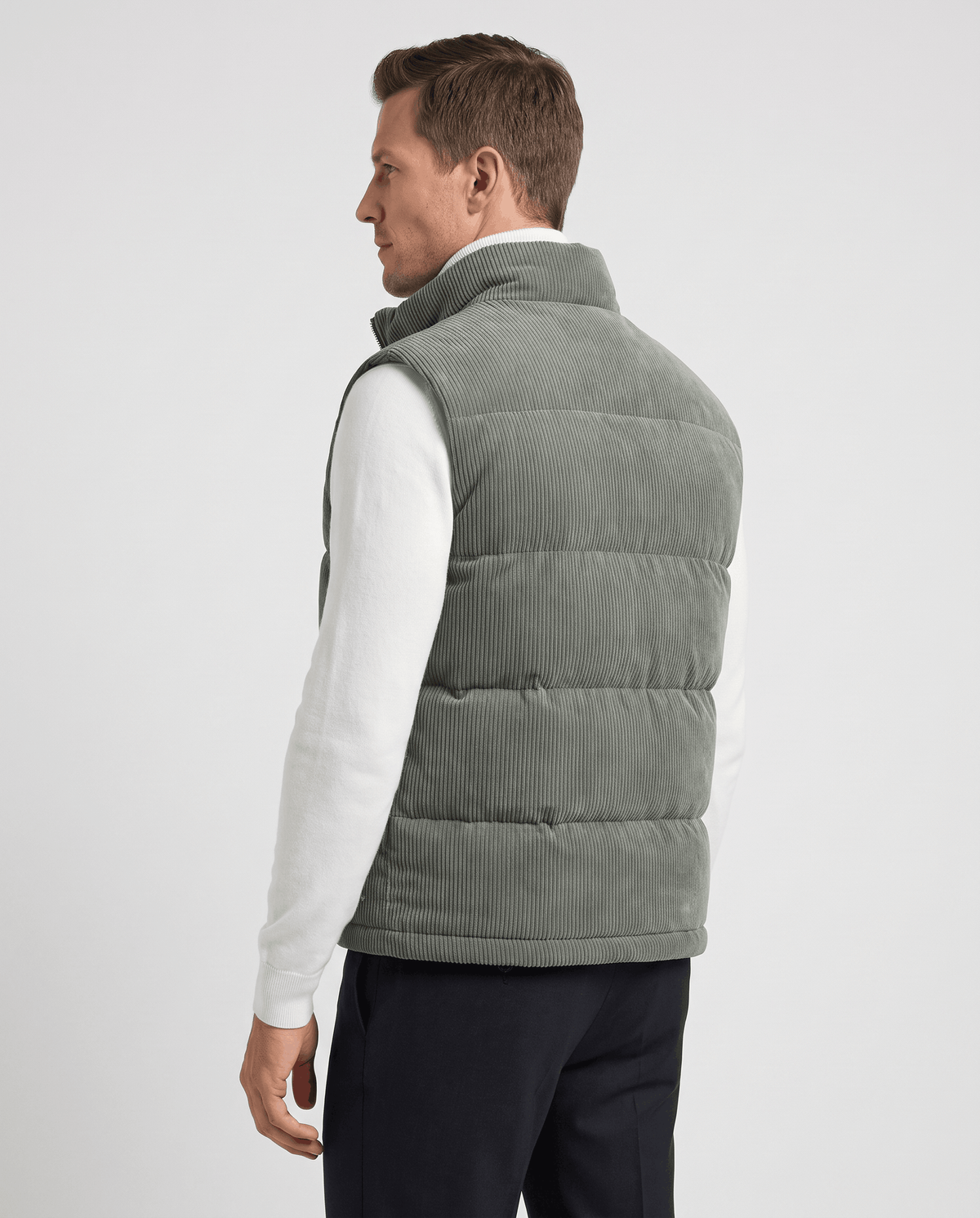 Back view of green corduroy vest with quilted panels over a white sweater