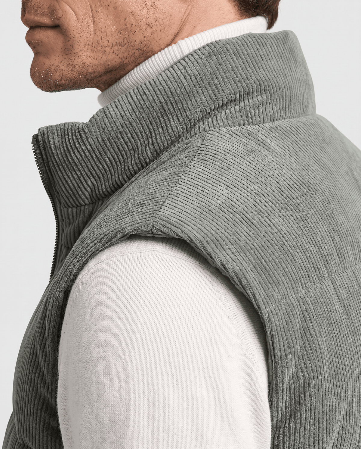 Side close-up of green corduroy vest showing the ribbed texture and stand collar