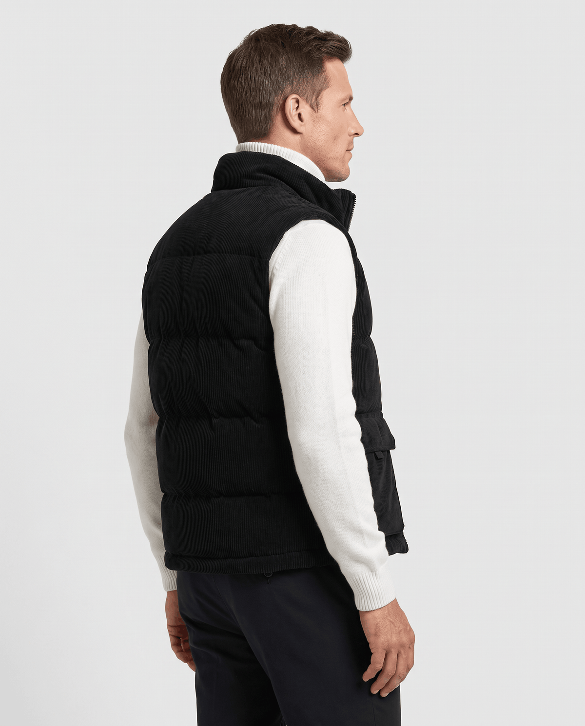 Back view of black corduroy vest over a white sweater and dark trousers