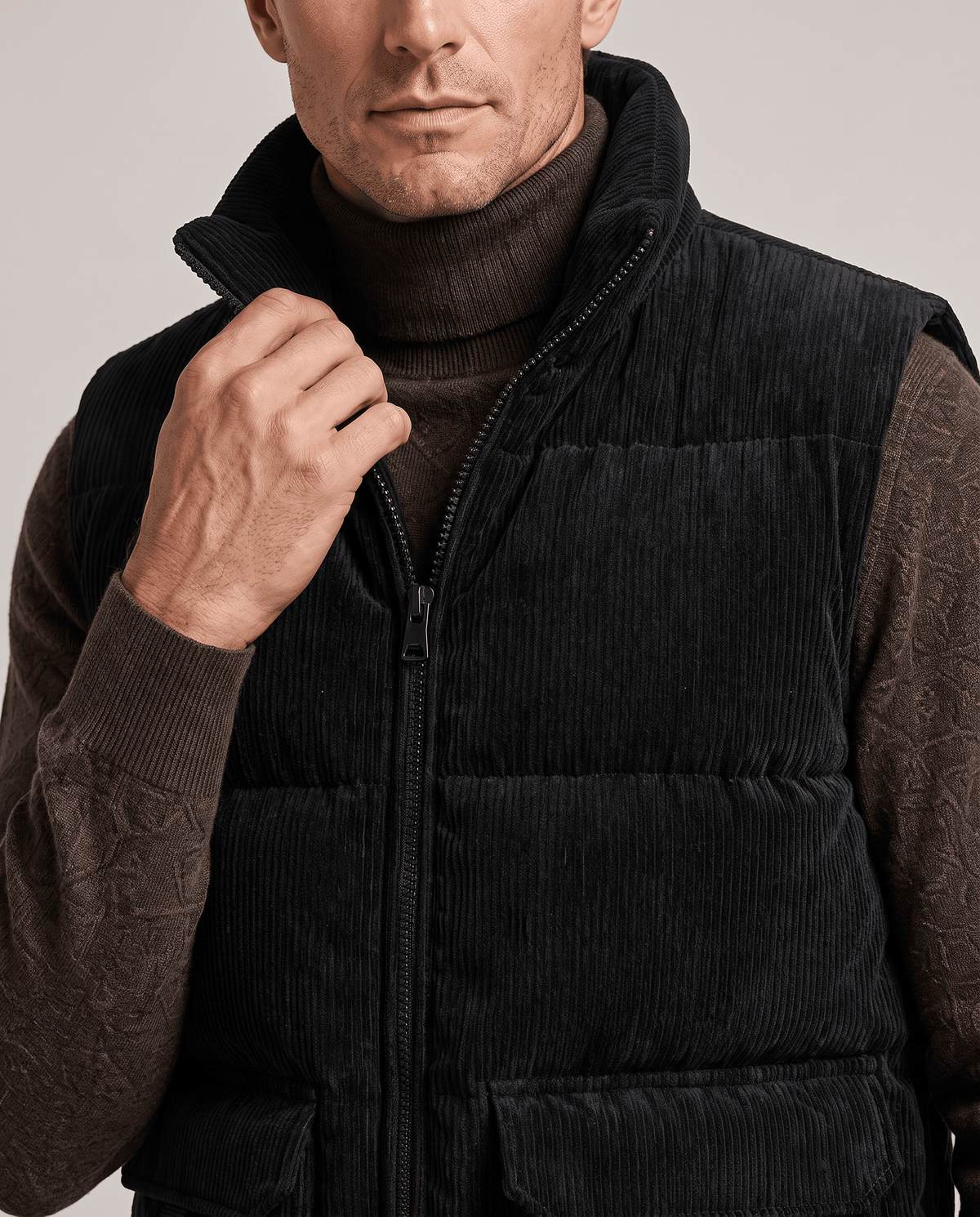 Close-up of black corduroy vest with hand on the zip at the stand collar