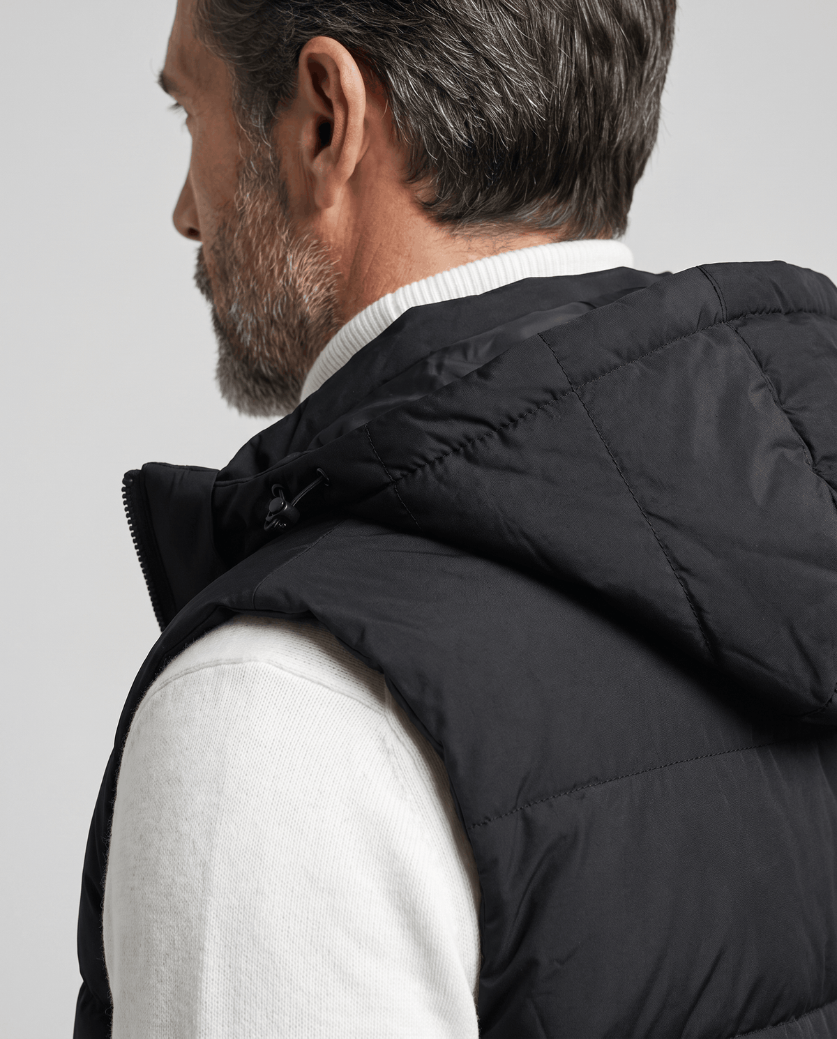 Rear view of black padded vest hood and quilted shoulder