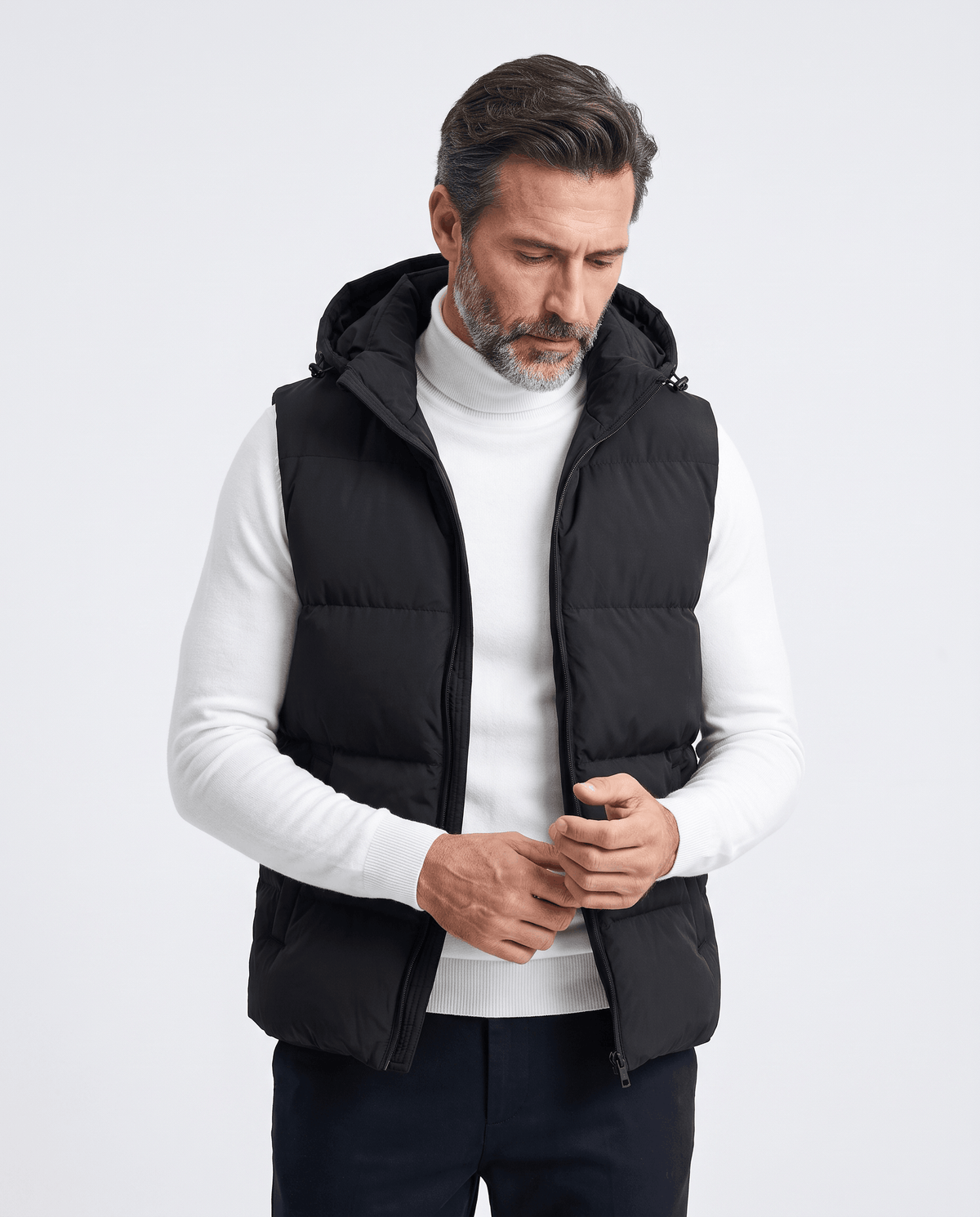 Man closing the zip of a black padded hooded vest