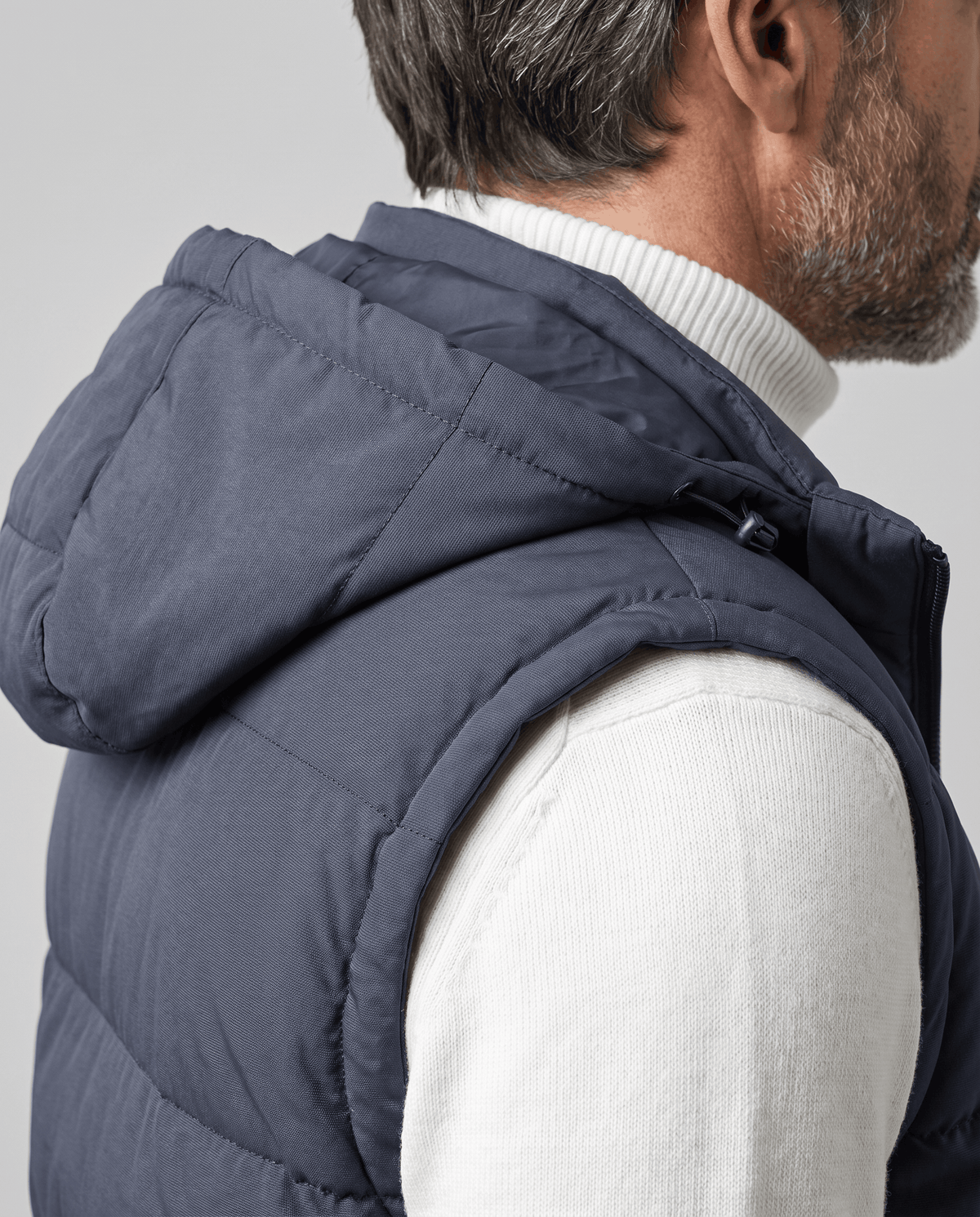 Side view of blue-gray padded vest hood and sleeveless armhole