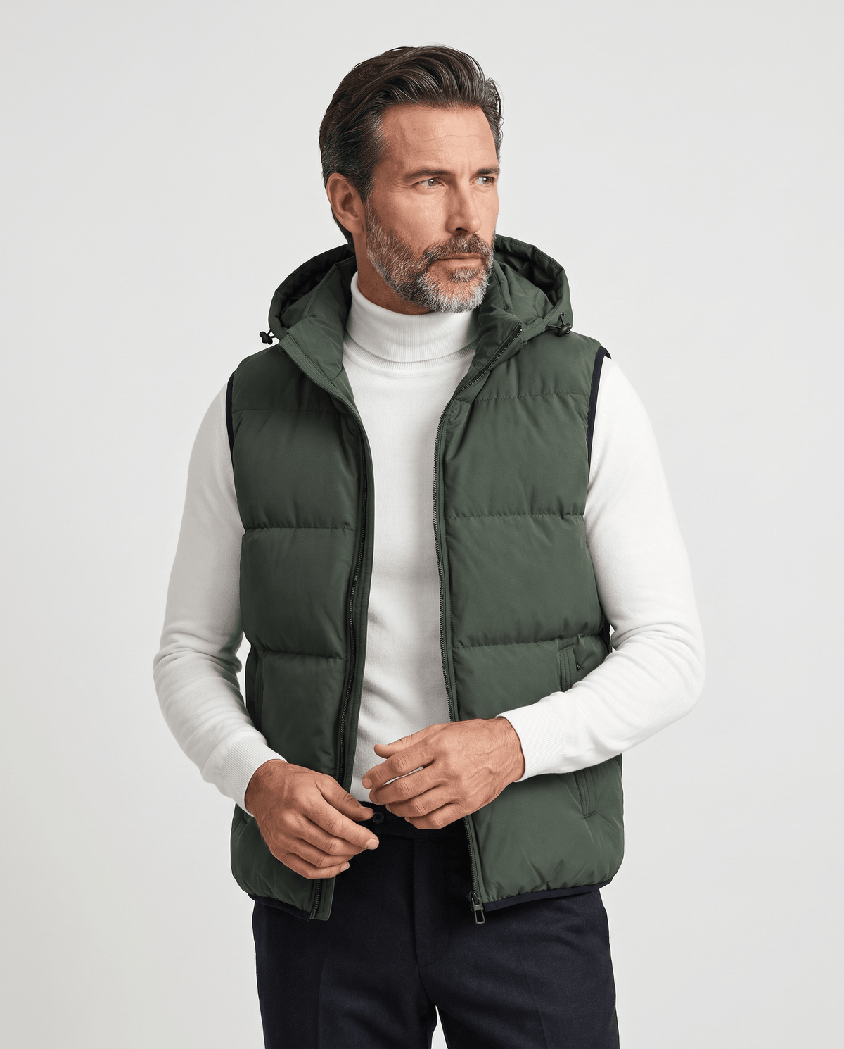 Men's military green padded hooded vest worn over a white turtleneck