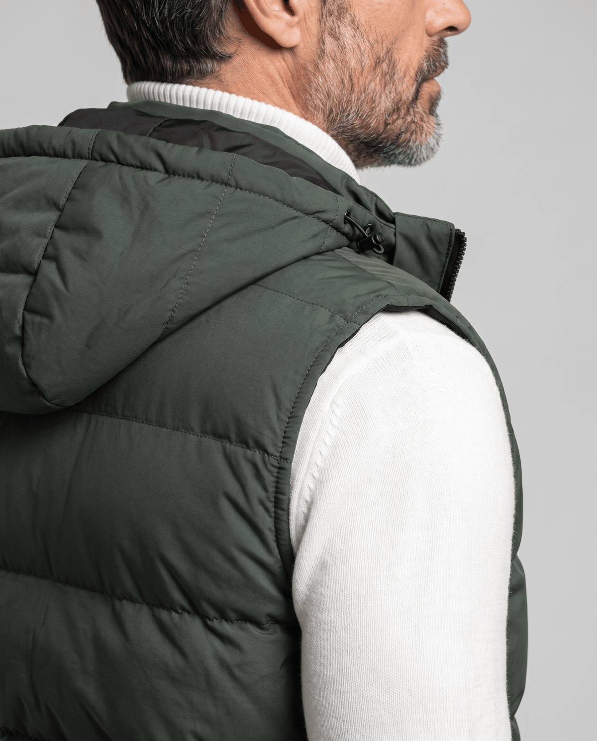 Side view of military green padded vest hood and sleeveless armhole