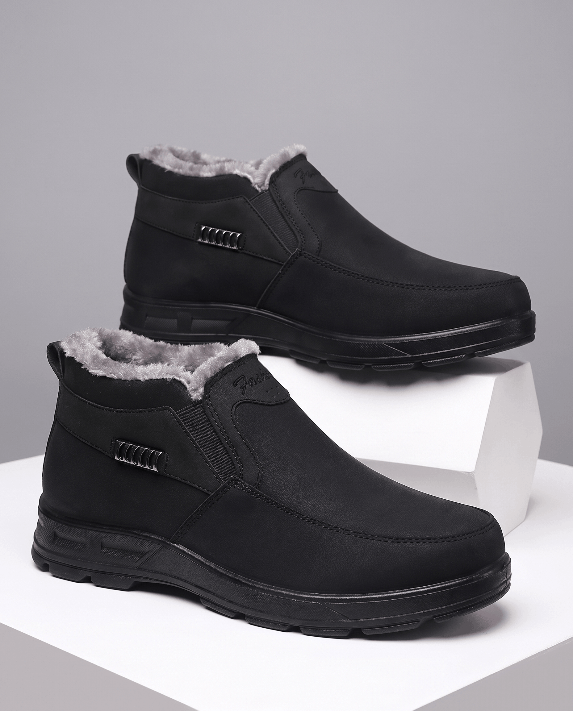 Black fleece-lined slip-on ankle boots with rugged rubber soles displayed on white blocks.