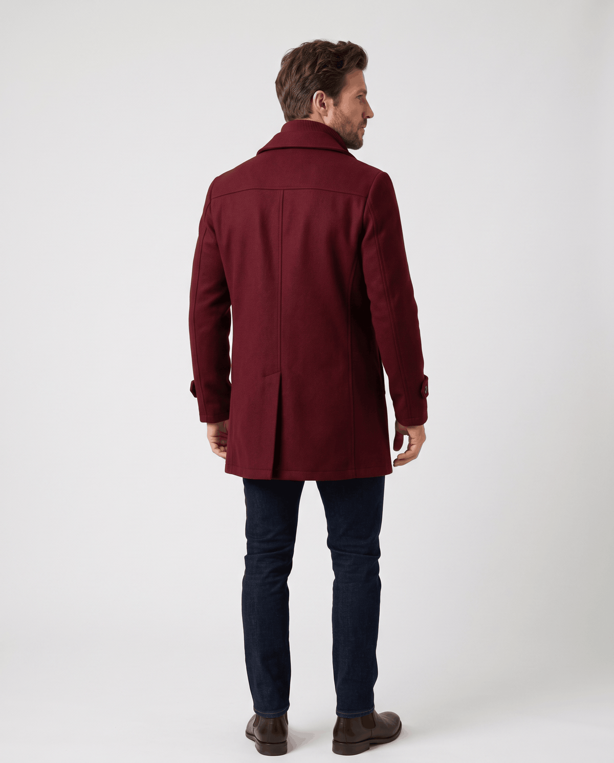 Back view of the burgundy overcoat worn with dark jeans and brown shoes