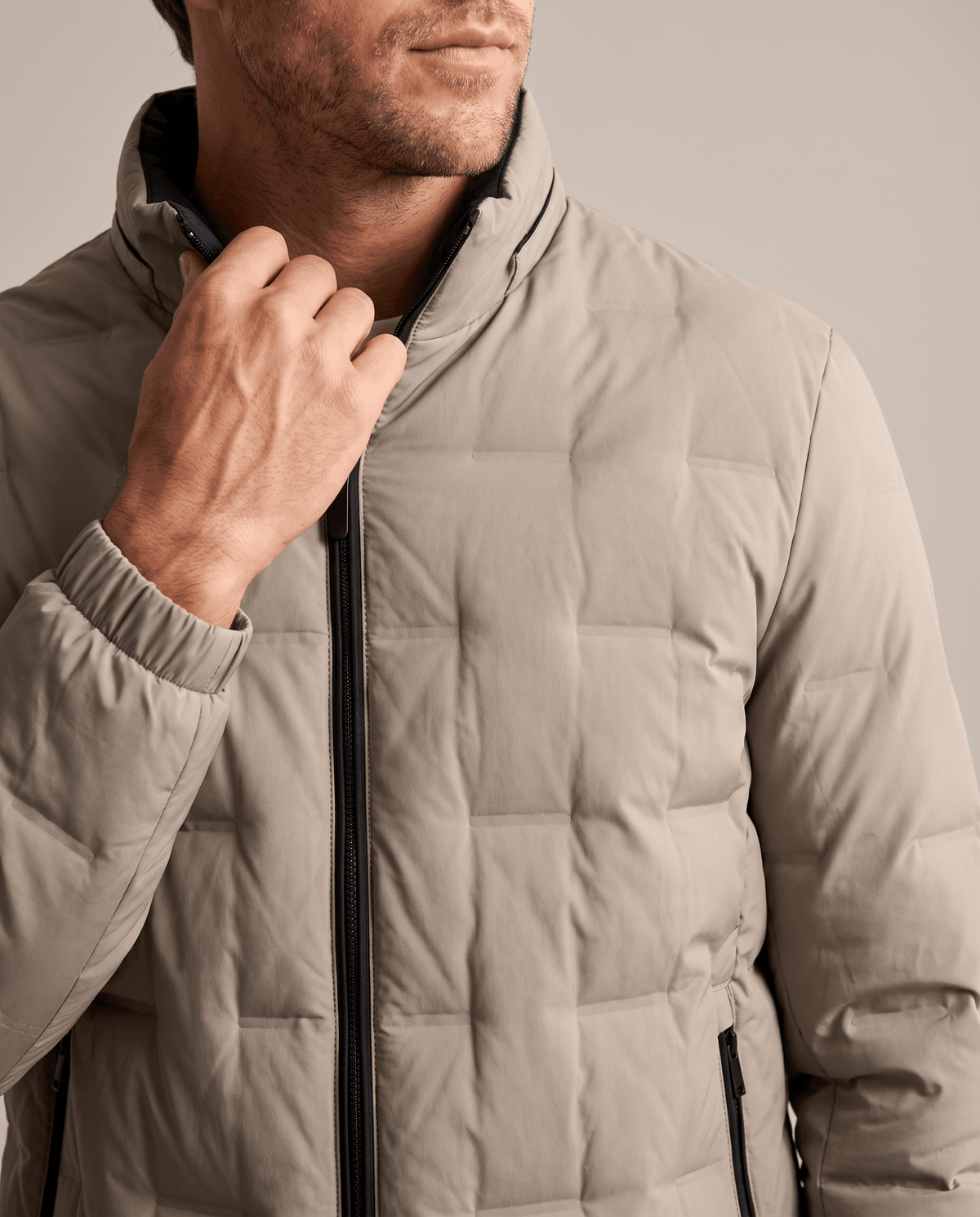 Close-up of the beige Sutton quilted down jacket stand collar, front zip and elasticated cuff