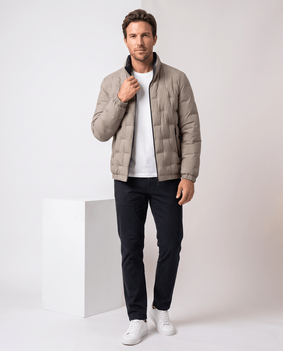 Man wearing the beige Sutton quilted down jacket over a white tee with dark jeans