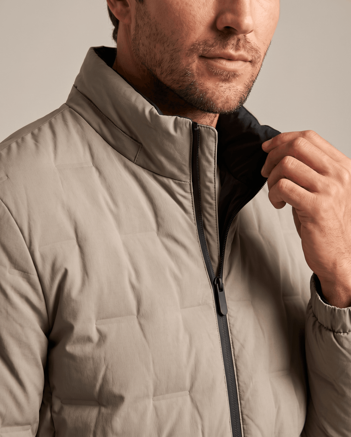 Detail of the beige Sutton quilted down jacket stand collar showing the dark inner collar lining