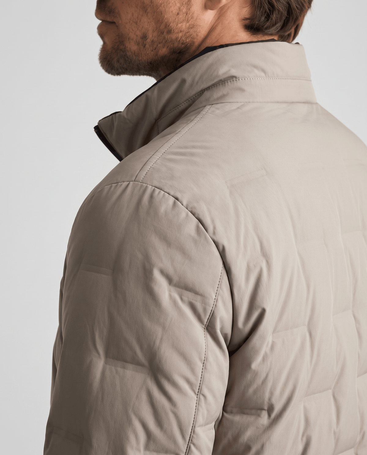 Shoulder detail of the beige Sutton quilted down jacket showing square block quilting