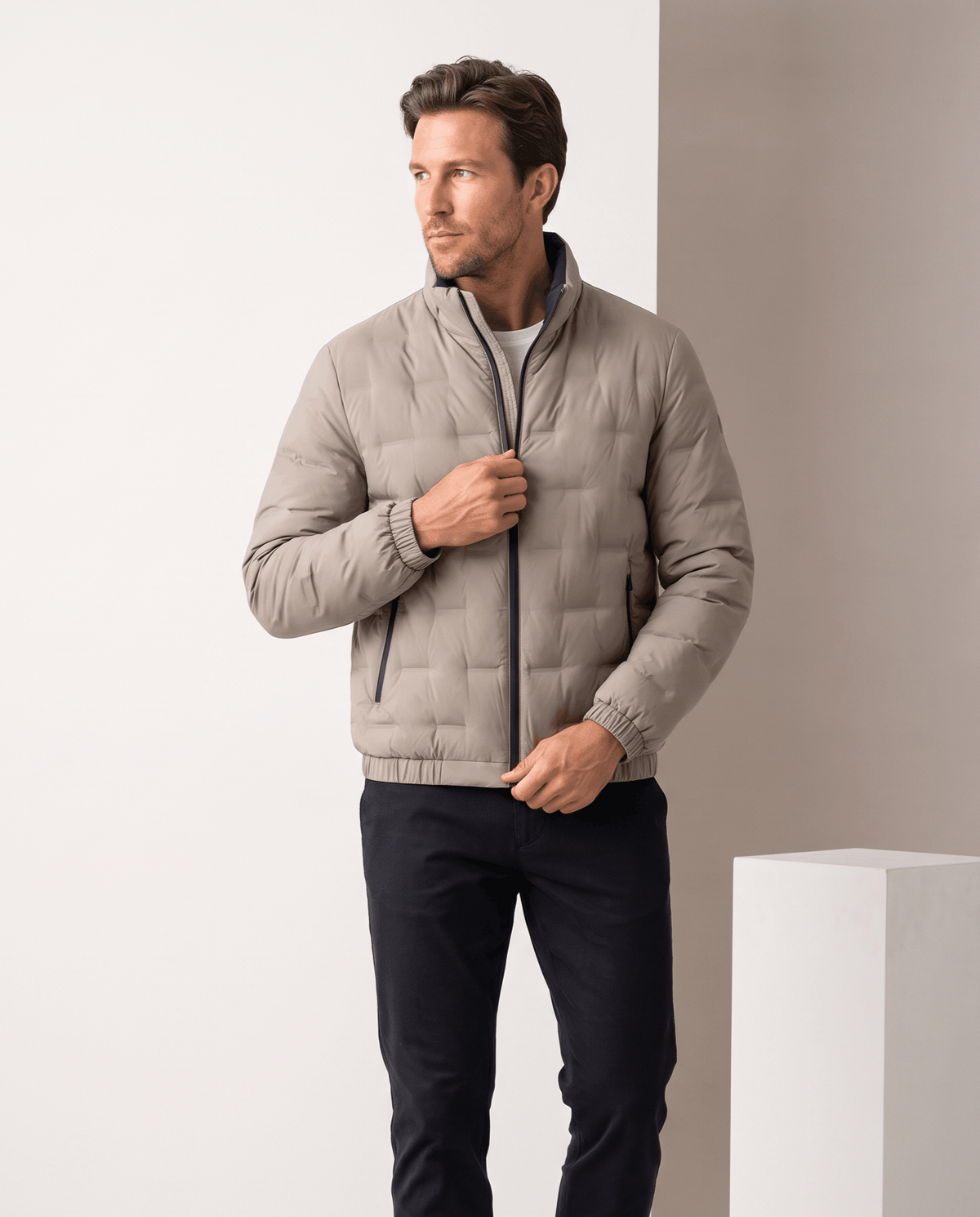 Man wearing the beige Sutton quilted down jacket open, showing the dark contrast inner lining and stand collar